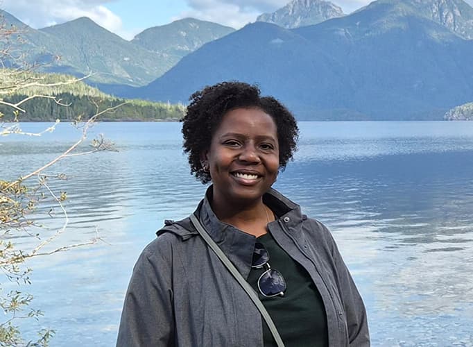 Dominique standing in front of a lake.